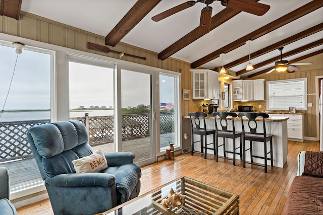 living area with ceiling fan, light wood-style floors, and wood walls