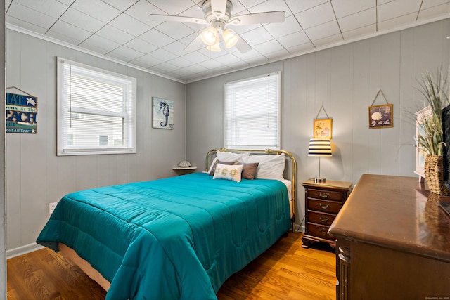 bedroom with multiple windows, crown molding, wood finished floors, and a ceiling fan