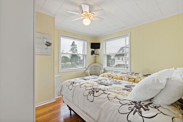 bedroom featuring wood finished floors, crown molding, and ceiling fan