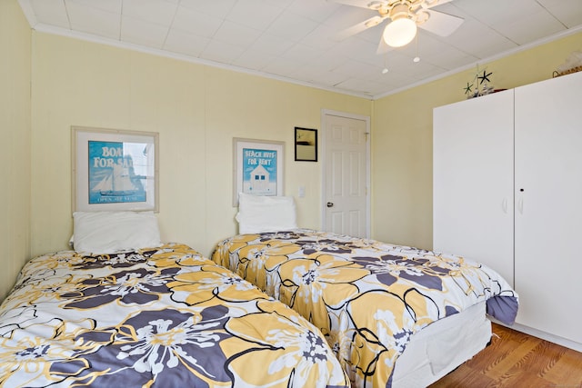 bedroom featuring crown molding, wood finished floors, and ceiling fan