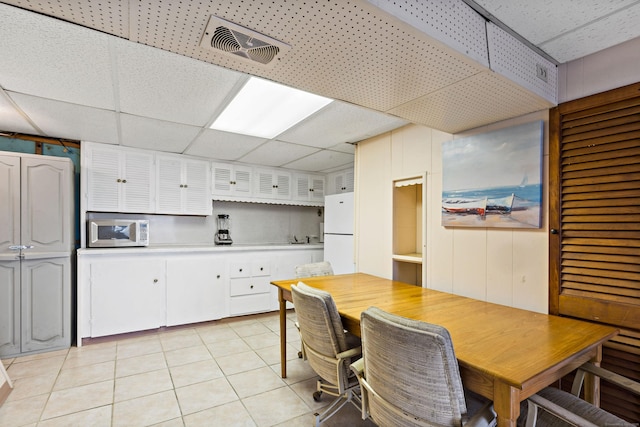 dining space with a drop ceiling and light tile patterned floors