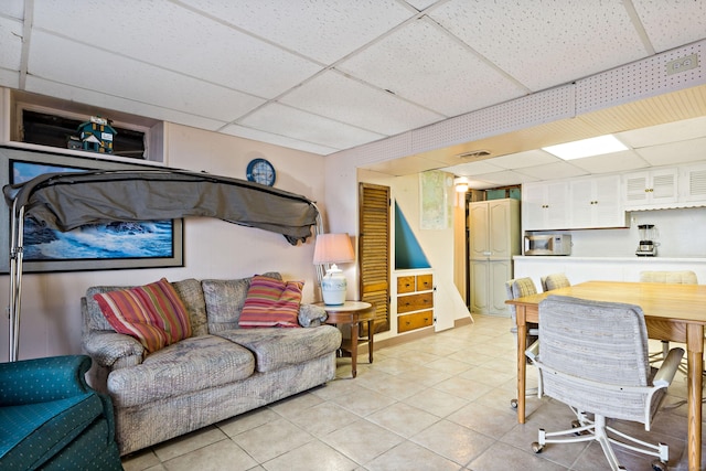 living area featuring a drop ceiling and light tile patterned floors