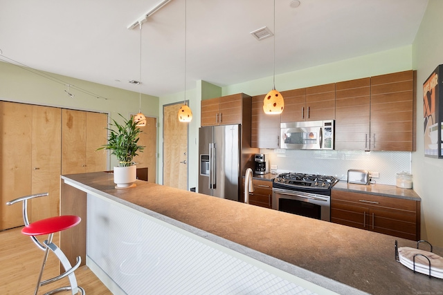 33 N Water St Unit 505, Norwalk, CT 06854 - kitchen featuring stainless steel appliances, decorative backsplash, light wood-style flooring, brown cabinets, and pendant lighting