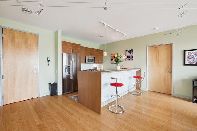 33 N Water St Unit 505, Norwalk, CT 06854 - kitchen with stainless steel appliances, rail lighting, brown cabinetry, and light wood-style flooring