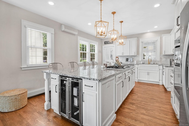 1676 Boulevard Blvd, West Hartford, CT 06107 - kitchen featuring a center island, a chandelier, a wall mounted AC, white cabinetry, and light wood-style floors