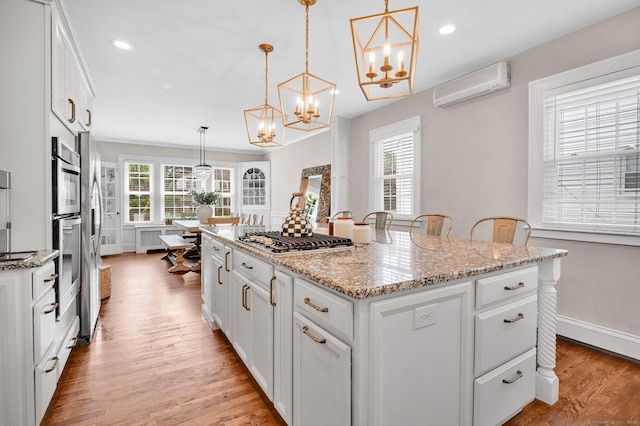 1676 Boulevard Blvd, West Hartford, CT 06107 - kitchen featuring stainless steel gas stovetop, a chandelier, a wall mounted AC, light wood-type flooring, and a kitchen island