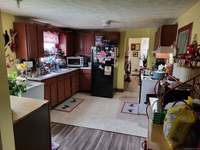 267 Chapman St, New Britain, CT 06051 - kitchen featuring freestanding refrigerator, white microwave, light countertops, a textured ceiling, and light wood-style flooring