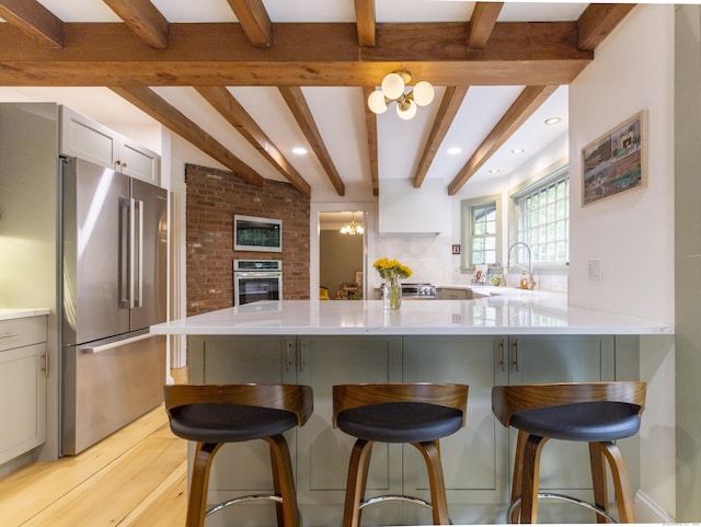 17 Kathleen Dr, Stratford, CT 06614 - kitchen featuring stainless steel appliances, beamed ceiling, light countertops, a breakfast bar area, and a peninsula