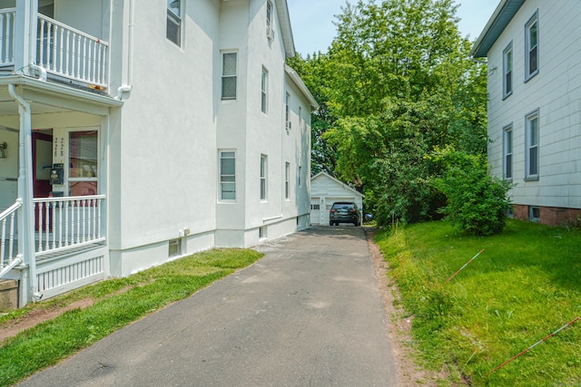 228 Elm St, Meriden, CT 06450 - view of home's exterior with a balcony, a garage, an outdoor structure, stucco siding, and a lawn