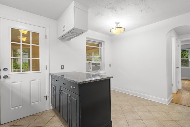 80 Holly St, Milford, CT 06460 - kitchen featuring arched walkways, cooling unit, light tile patterned flooring, white cabinets, and a textured ceiling