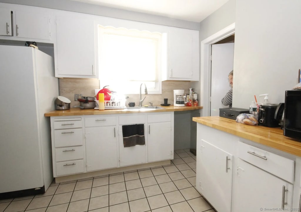 120 S Main St, Manchester, CT 06040 - kitchen featuring freestanding refrigerator, butcher block counters, white cabinets, light tile patterned floors, and tasteful backsplash