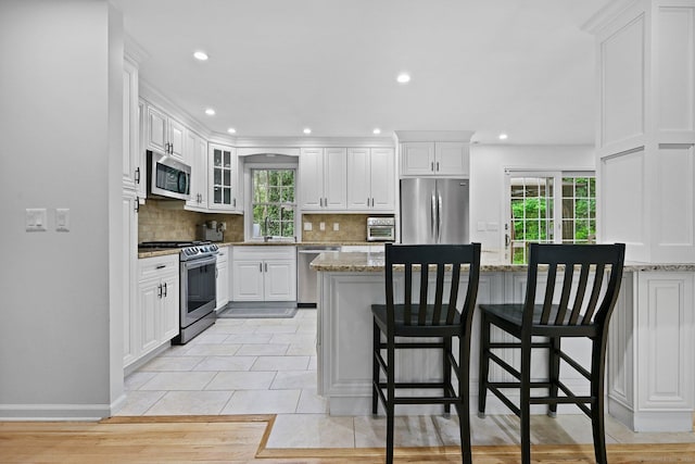 10 Eric Ct, Norwalk, CT 06851 - kitchen featuring stainless steel appliances, backsplash, white cabinets, a kitchen bar, and recessed lighting