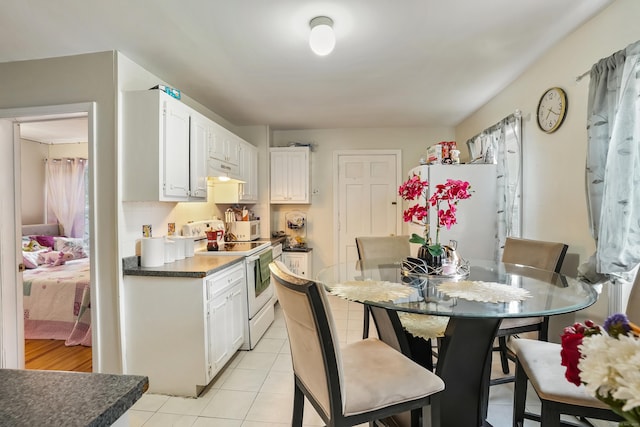 17 Pleasant St, Danbury, CT 06810 - kitchen with white appliances, under cabinet range hood, light tile patterned flooring, white cabinetry, and dark countertops