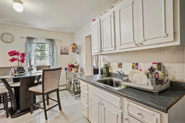 17 Pleasant St, Danbury, CT 06810 - kitchen featuring dark countertops, backsplash, light tile patterned floors, a baseboard radiator, and white cabinetry
