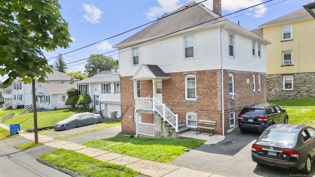 53 Norton St, Bristol, CT 06010 - view of property featuring a chimney, brick siding, a front lawn, and asphalt driveway
