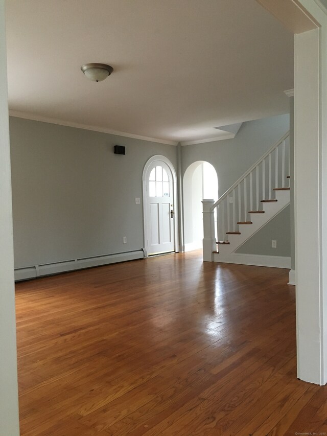 1333 Blue Hills Ave, Bloomfield, CT 06002 - empty room featuring a baseboard heating unit, arched walkways, ornamental molding, stairway, and wood finished floors