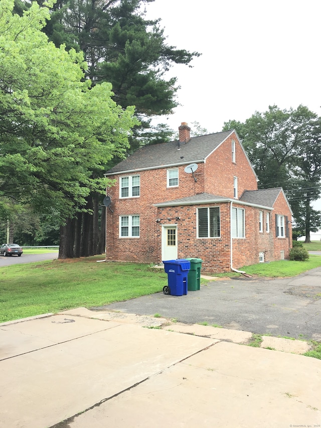 1333 Blue Hills Ave, Bloomfield, CT 06002 - back of house with a chimney, a lawn, brick siding, and asphalt driveway