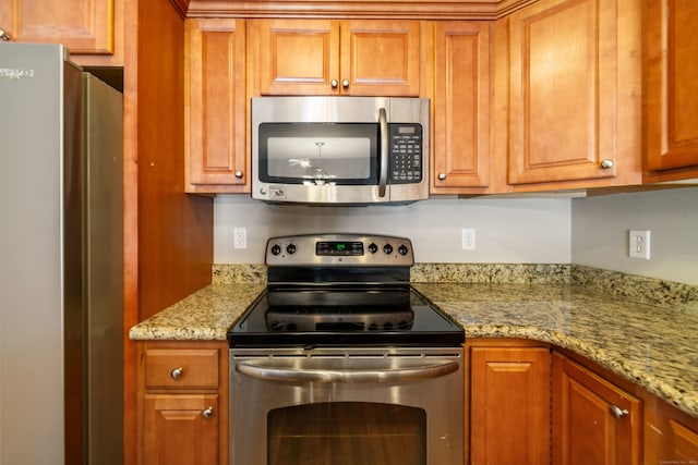 44 Forshaw Ave Unit 44, Plainville, CT 06062 - kitchen featuring appliances with stainless steel finishes, brown cabinetry, and light stone counters