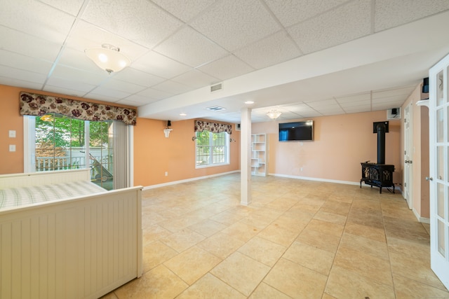 44 Forshaw Ave Unit 44, Plainville, CT 06062 - unfurnished living room featuring a drop ceiling, a wood stove, and light tile patterned flooring