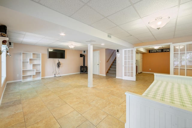 44 Forshaw Ave Unit 44, Plainville, CT 06062 - finished below grade area with a paneled ceiling, stairs, a wood stove, and light tile patterned floors