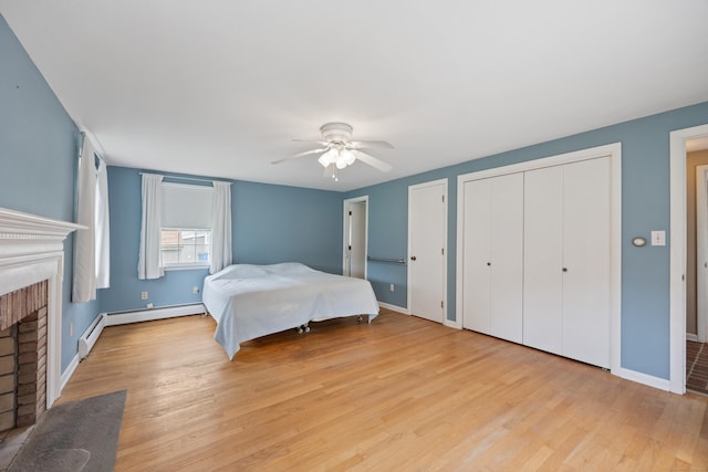 1519 Tuttle Ave, Wallingford, CT 06492 - bedroom with a fireplace, wood finished floors, a baseboard radiator, a ceiling fan, and two closets