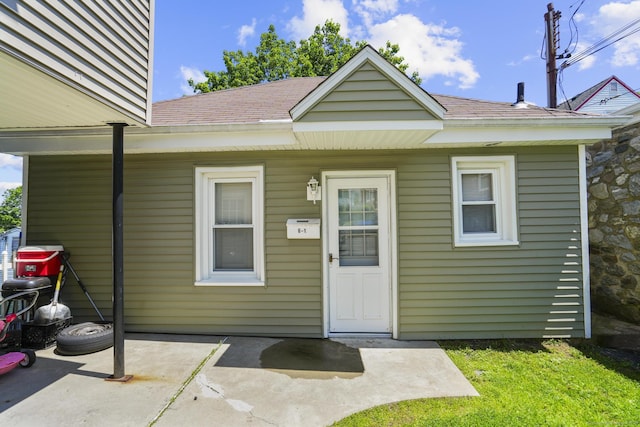6 Houghton St, Bristol, CT 06010 - doorway to property with a shingled roof, a patio, and a lawn