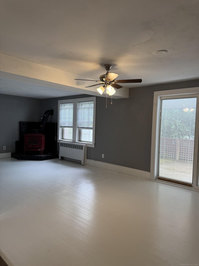 58 Barlow St, North Canaan, CT 06018 - unfurnished room featuring radiator heating unit, plenty of natural light, a wood stove, and ceiling fan