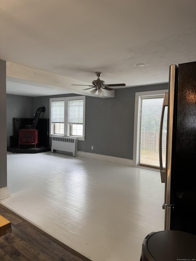 58 Barlow St, North Canaan, CT 06018 - unfurnished living room with radiator, healthy amount of natural light, a wood stove, and a ceiling fan