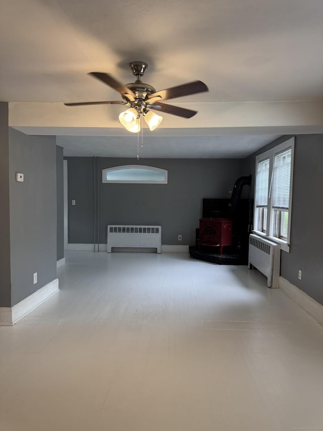 58 Barlow St, North Canaan, CT 06018 - unfurnished living room featuring radiator heating unit, a wood stove, and a ceiling fan