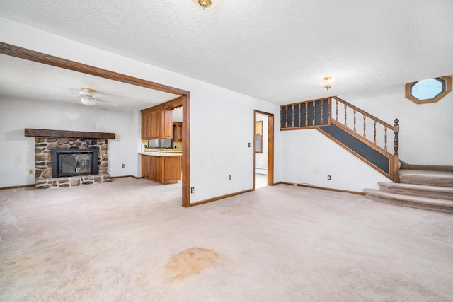 546 S Quaker Ln, West Hartford, CT 06110 - unfurnished living room with stairway, light colored carpet, a ceiling fan, a textured ceiling, and a stone fireplace