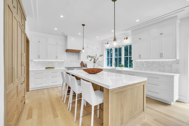 133 E Ave Unit A, New Canaan, CT 06840 - kitchen featuring custom range hood, light wood-type flooring, tasteful backsplash, light countertops, and recessed lighting
