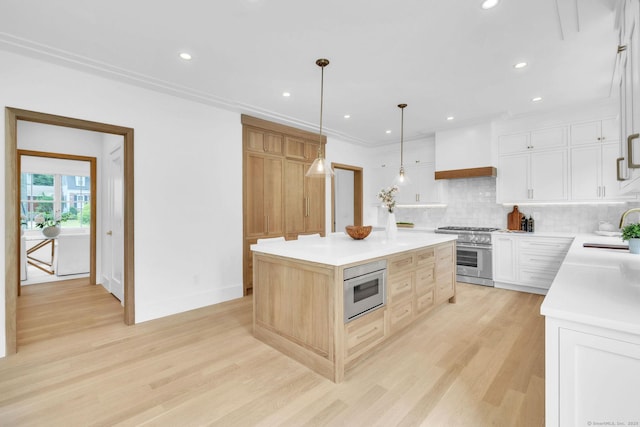 133 E Ave Unit A, New Canaan, CT 06840 - kitchen with stainless steel stove, custom exhaust hood, a kitchen island, light wood-type flooring, and tasteful backsplash