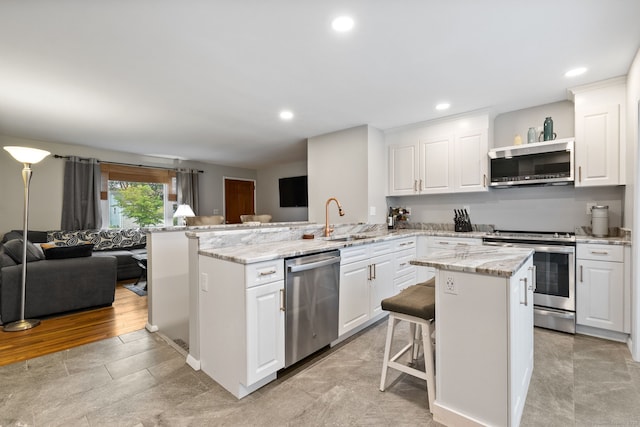 301 Pondview Dr, Southington, CT 06489 - kitchen featuring stainless steel appliances, open floor plan, a peninsula, white cabinets, and a kitchen island