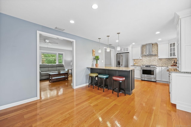 142 Raffia Rd, Enfield, CT 06082 - kitchen with wall chimney range hood, appliances with stainless steel finishes, a breakfast bar, white cabinetry, and a peninsula