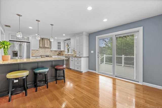 142 Raffia Rd, Enfield, CT 06082 - kitchen featuring stainless steel appliances, wall chimney range hood, a kitchen breakfast bar, white cabinetry, and glass insert cabinets