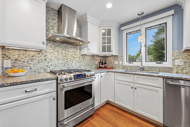 142 Raffia Rd, Enfield, CT 06082 - kitchen featuring stainless steel appliances, wall chimney range hood, decorative backsplash, white cabinets, and hanging light fixtures