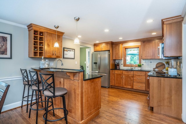 11 Craigmoor Rd, West Hartford, CT 06107 - kitchen with stainless steel fridge with ice dispenser, dark countertops, a peninsula, brown cabinetry, and ornamental molding