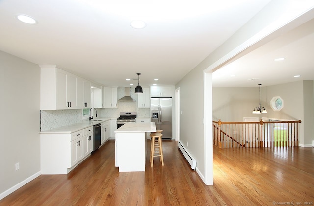 5 Great Meadow Dr, North Haven, CT 06473 - kitchen with stainless steel appliances, a baseboard radiator, wall chimney exhaust hood, a kitchen bar, and recessed lighting