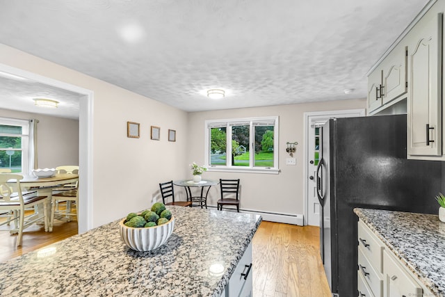 45 Neelans Rd, Enfield, CT 06082 - kitchen with a baseboard radiator, light wood-style flooring, light stone counters, and freestanding refrigerator