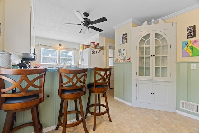 1092 Durham Rd, Guilford, CT 06437 - kitchen featuring white refrigerator with ice dispenser, ornamental molding, a peninsula, a ceiling fan, and a breakfast bar