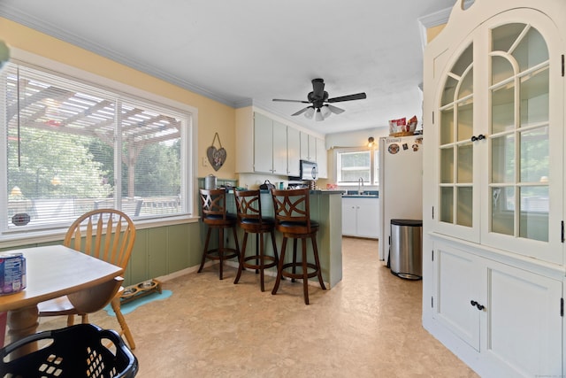 1092 Durham Rd, Guilford, CT 06437 - kitchen with a peninsula, white cabinets, freestanding refrigerator, ceiling fan, and a breakfast bar area