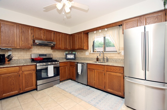 140 Thompson St Apt 16A, East Haven, CT 06513 - kitchen with stainless steel appliances, under cabinet range hood, brown cabinets, and decorative backsplash