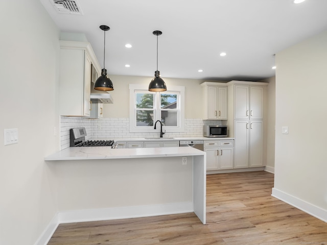8 Platt St, Norwalk, CT 06855 - kitchen featuring stainless steel appliances, light countertops, a peninsula, backsplash, and light wood-type flooring