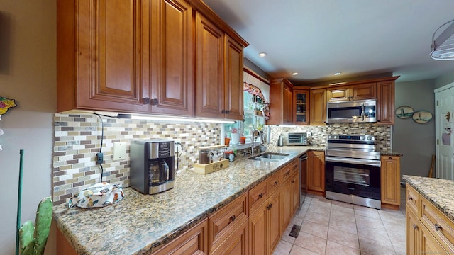 345 Goodwin St, East Hartford, CT 06108 - kitchen featuring stainless steel appliances, backsplash, light stone countertops, brown cabinetry, and light tile patterned floors