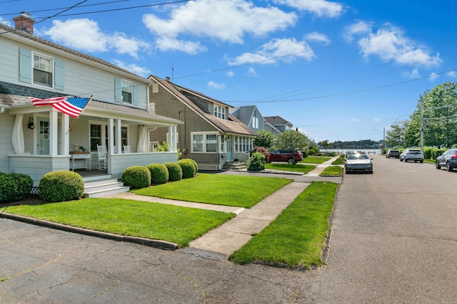 18 Wallace Ave, Norwalk, CT 06855 - view of front facade with a porch, a front lawn, a shingled roof, and a chimney