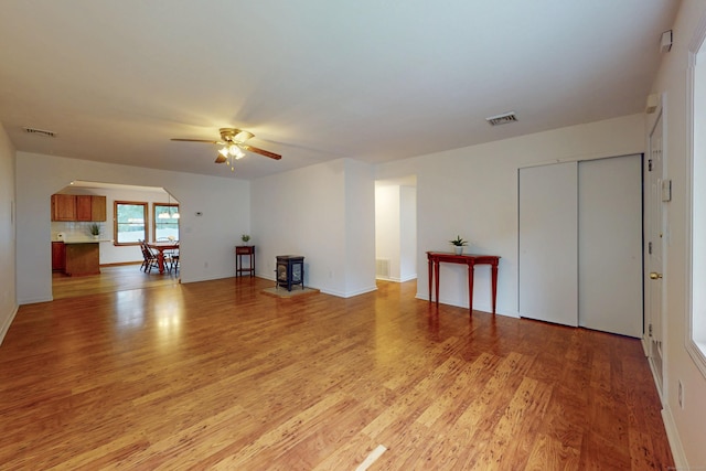 20 Hickory St, Danbury, CT 06810 - unfurnished living room featuring arched walkways, ceiling fan, light wood-style floors, and a wood stove