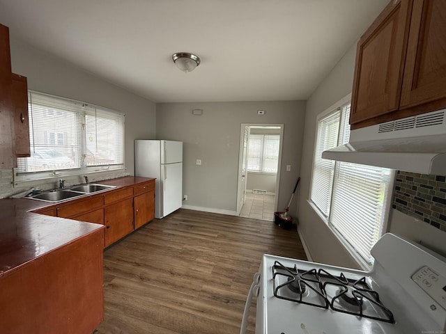 118 Cherry Ann St, New Haven, CT 06514 - kitchen with white appliances, under cabinet range hood, dark wood-style floors, brown cabinets, and dark countertops