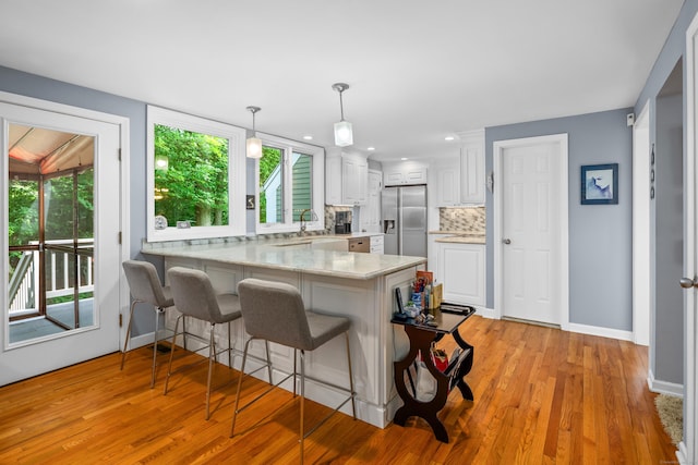 212 Richards Ave Apt 6, Norwalk, CT 06850 - kitchen with a peninsula, stainless steel fridge, backsplash, light countertops, and white cabinets