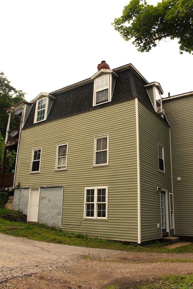 51 Main St, Thompson, CT 06255 - view of side of home featuring mansard roof, roof with shingles, a chimney, and a balcony