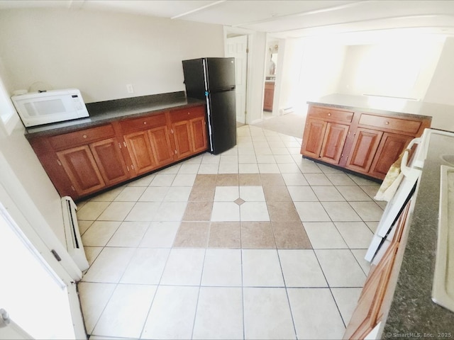 51 Main St, Thompson, CT 06255 - kitchen with freestanding refrigerator, white microwave, light tile patterned flooring, brown cabinetry, and dark countertops